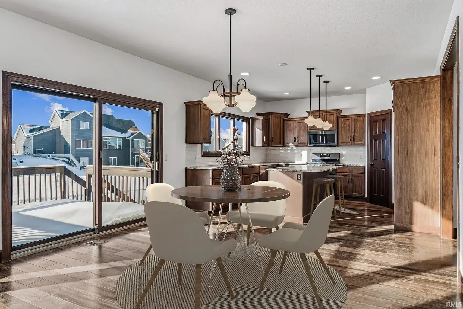 Modern kitchen and dining area with wooden cabinets, round table, and large sliding glass doors.