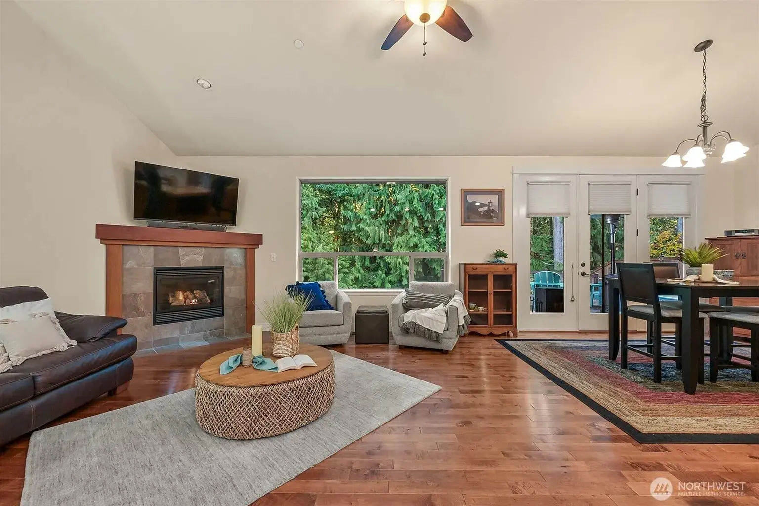 Spacious living room with fireplace, TV, large window, and dining area with table and chairs.