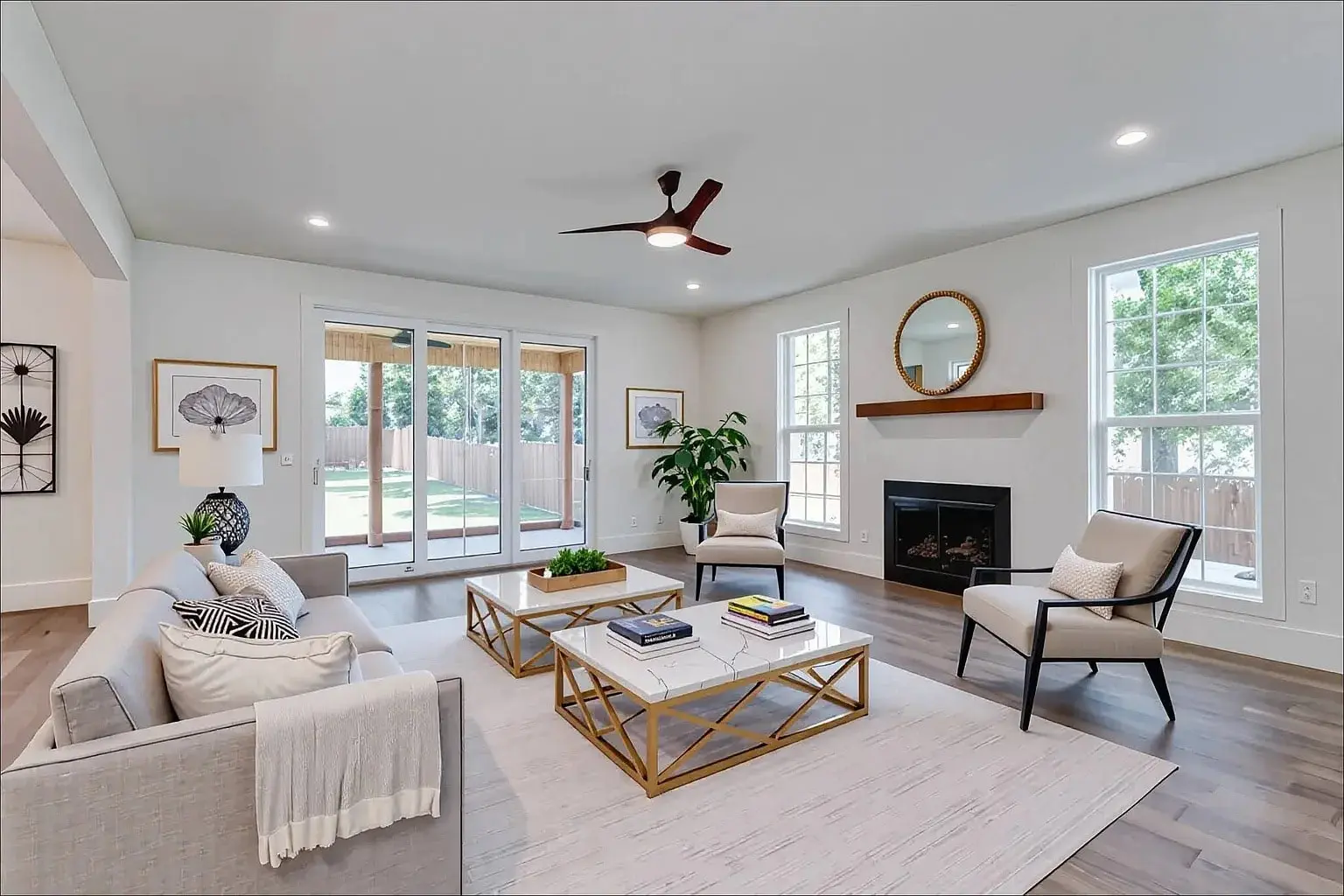 Modern living room with large windows, white walls, gray sofa, armchairs, and a central coffee table.