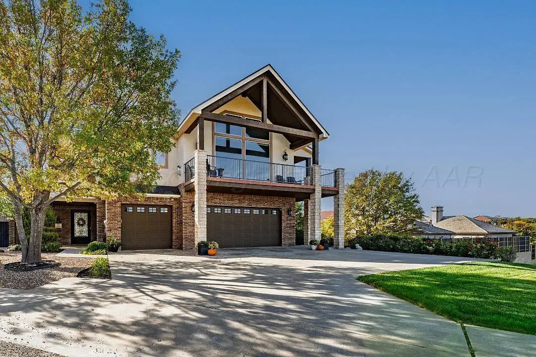 Modern two-story house with large windows, three garage doors, and a spacious driveway.