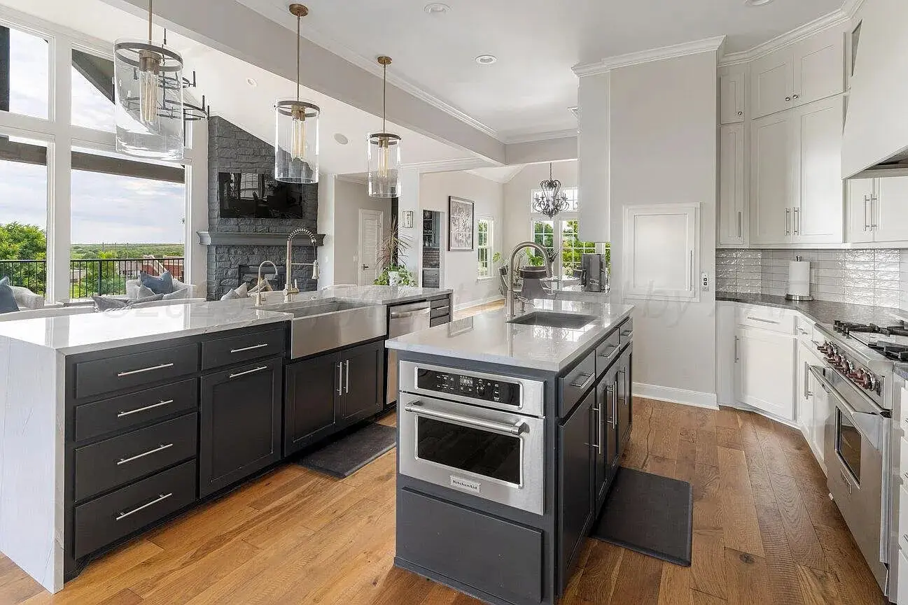 Modern kitchen with black and white cabinets, large island, and stainless steel appliances.