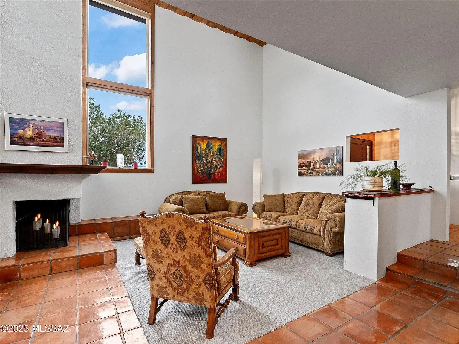 Living room with a fireplace, two sofas, an armchair, and artwork on white walls.