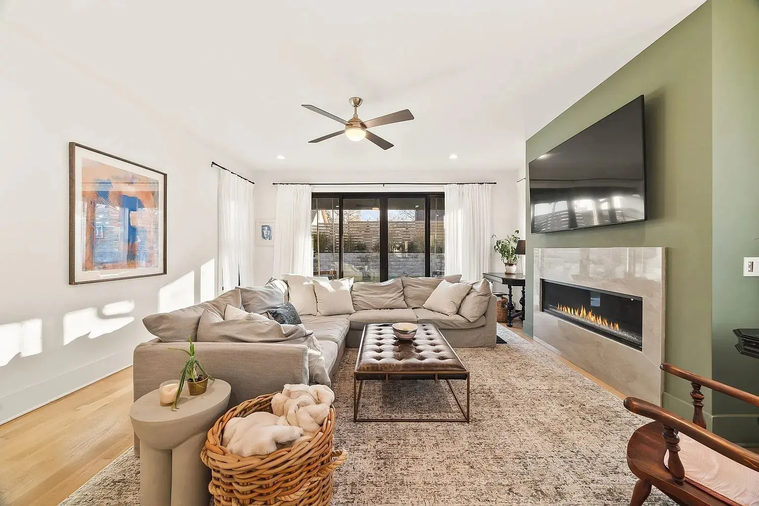 Modern living room with a large sectional sofa, wall-mounted TV, and a fireplace.