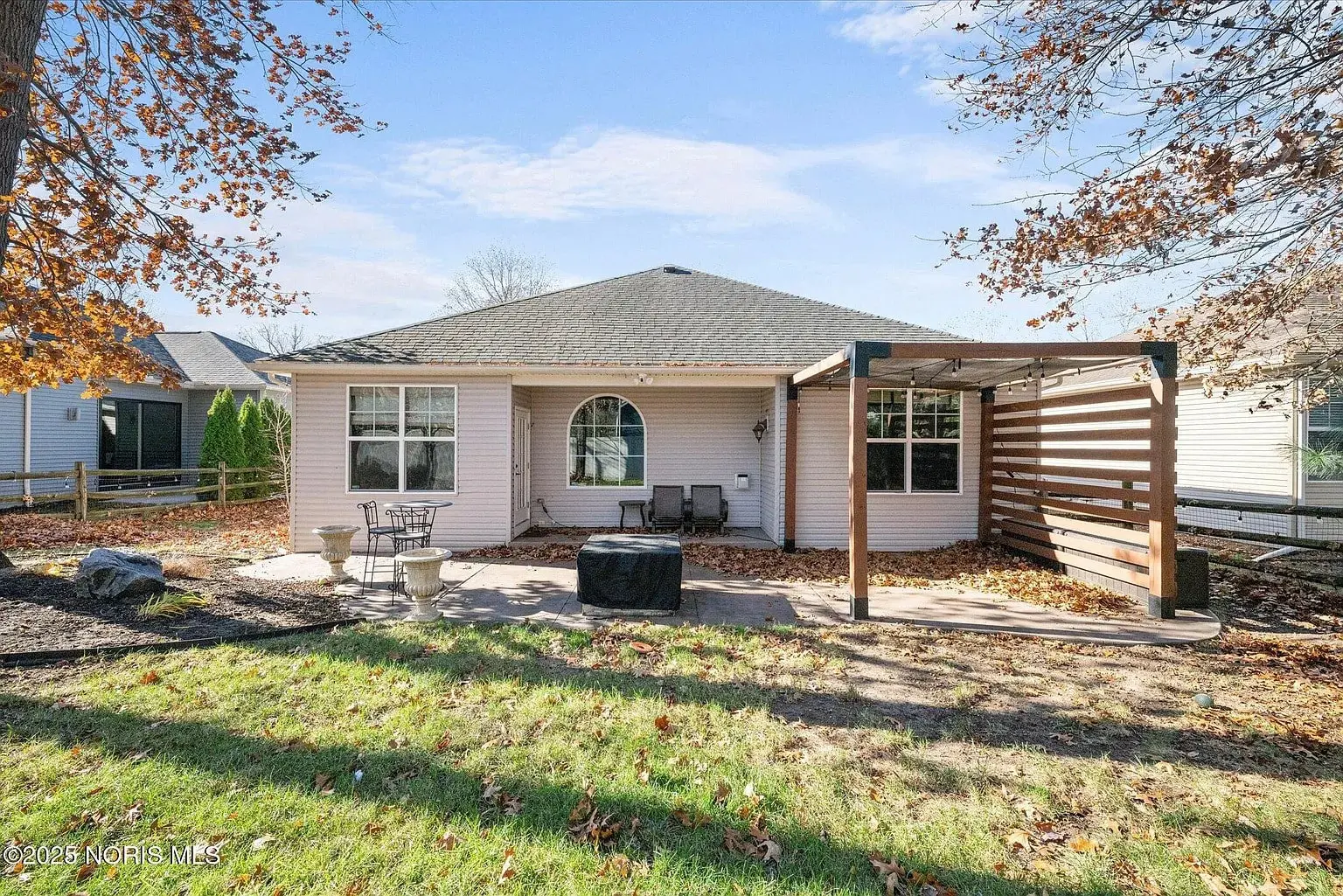 Single-story house with a patio, outdoor seating, and a pergola in a backyard setting.