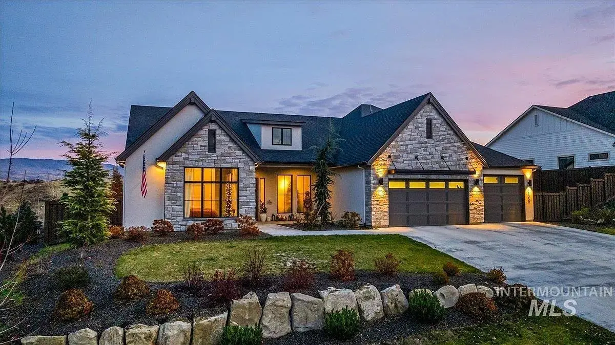 Modern house with stone facade, large windows, and a two-car garage at sunset.