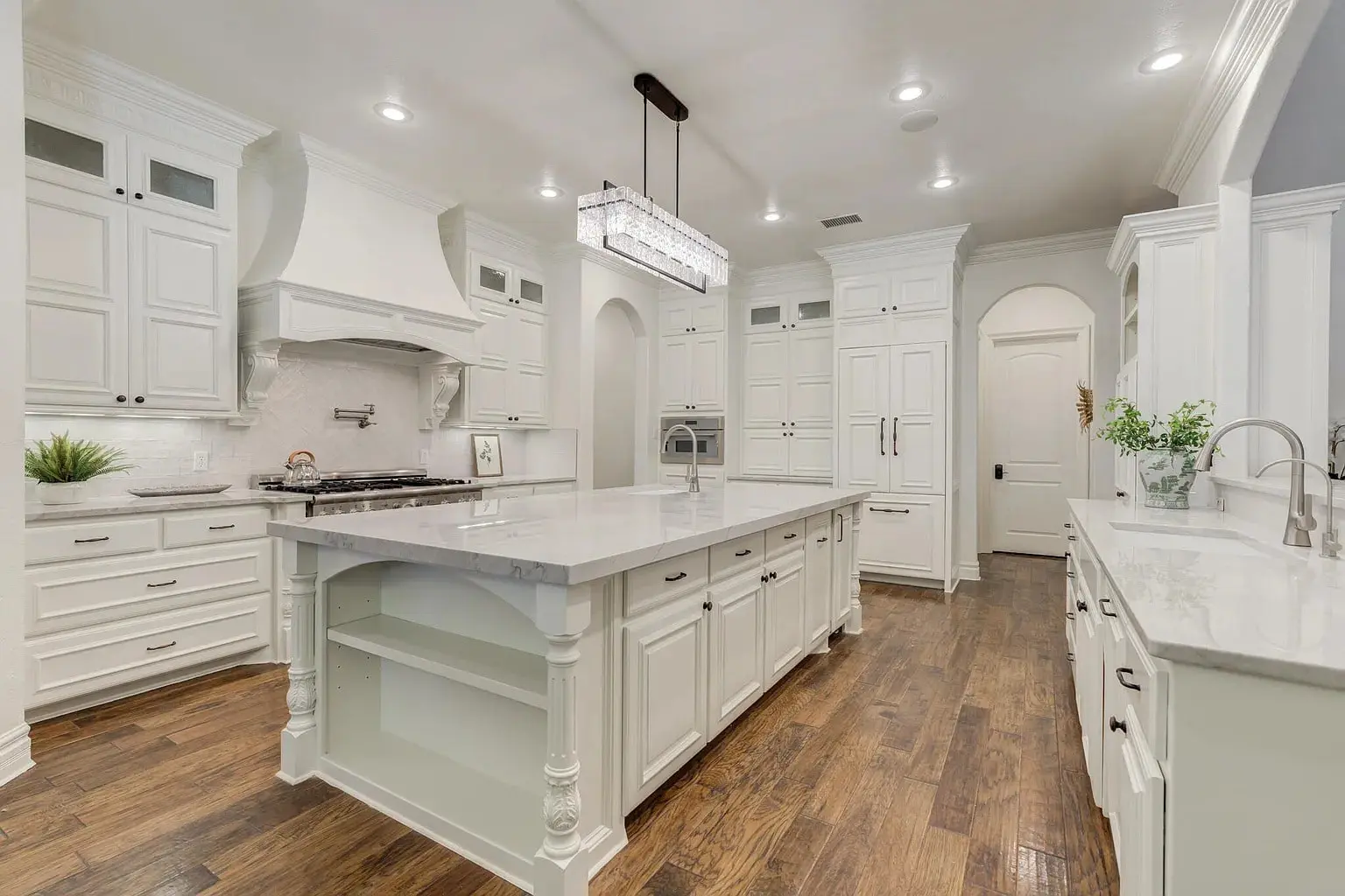 Spacious modern kitchen with white cabinets, large island, and hardwood floors.