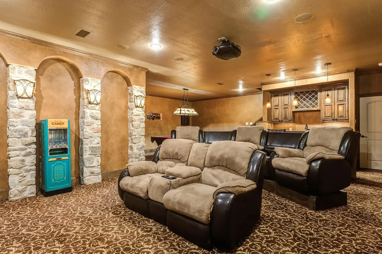 Home theater room with plush seating, a candy vending machine, and a projector.