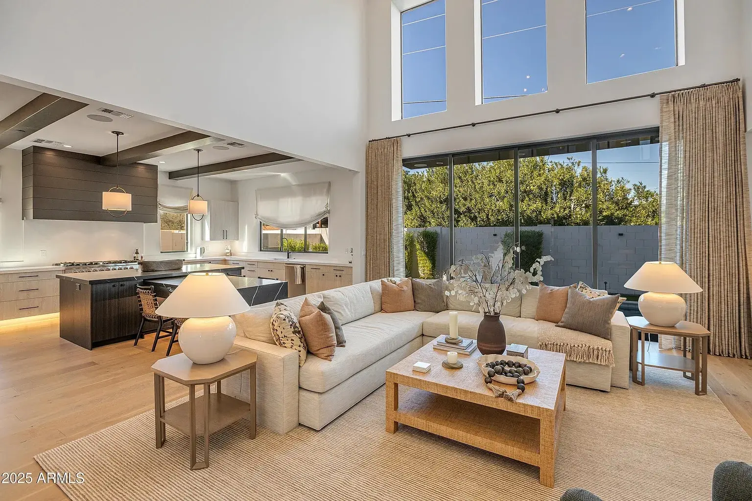 Spacious modern living room with large windows, sectional sofa, and open kitchen area.