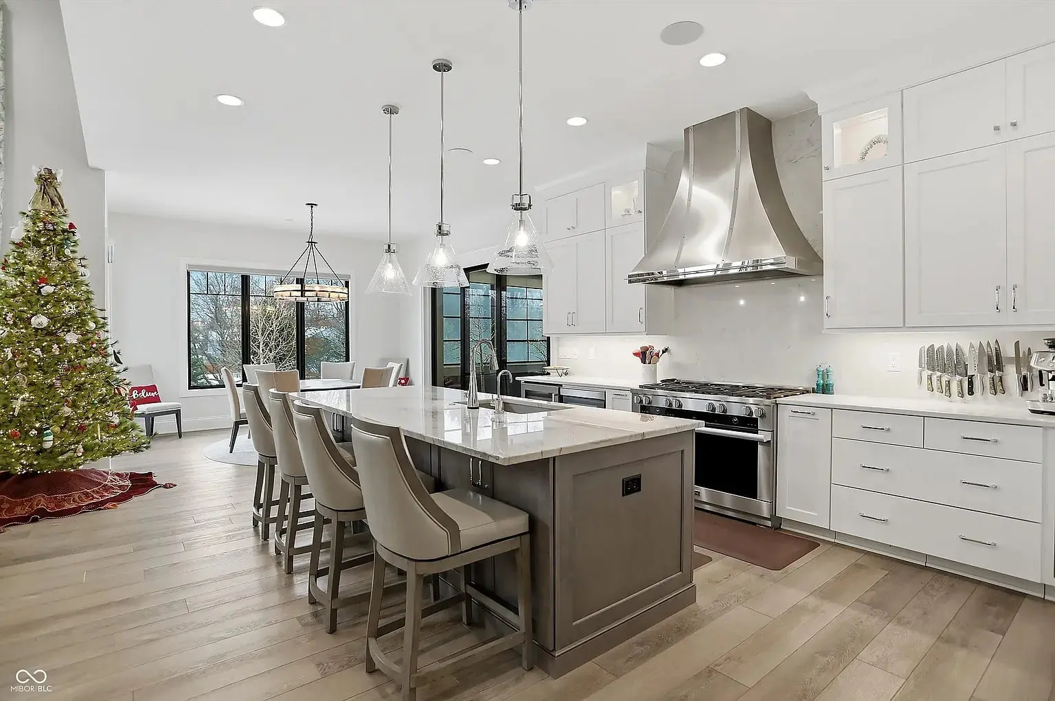 Modern kitchen with island, stainless steel appliances, and a Christmas tree in the dining area.