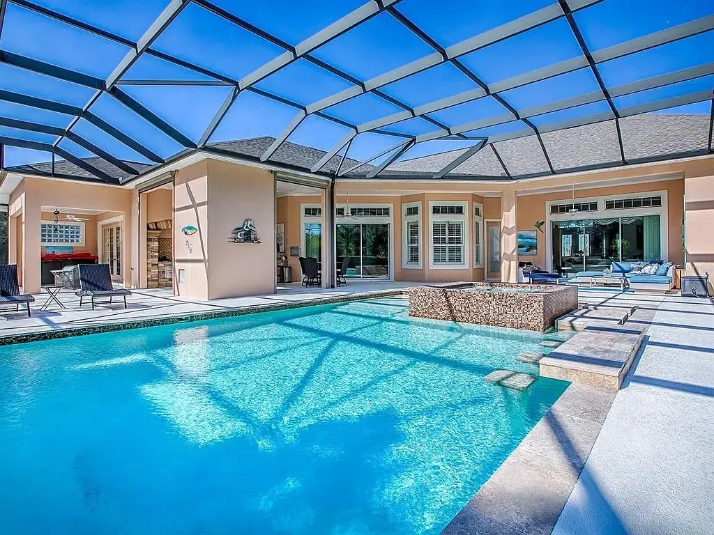 Spacious backyard with a screened-in pool, lounge chairs, and modern patio furniture.