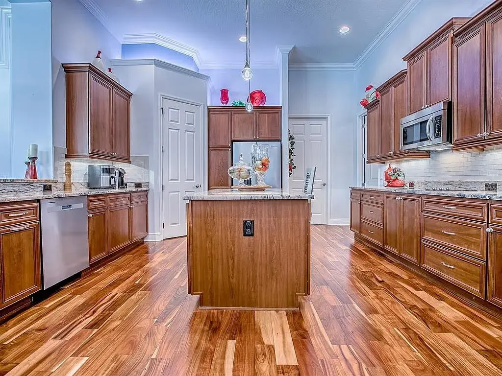 Spacious kitchen with wooden cabinets, island, stainless steel appliances, and hardwood floors.