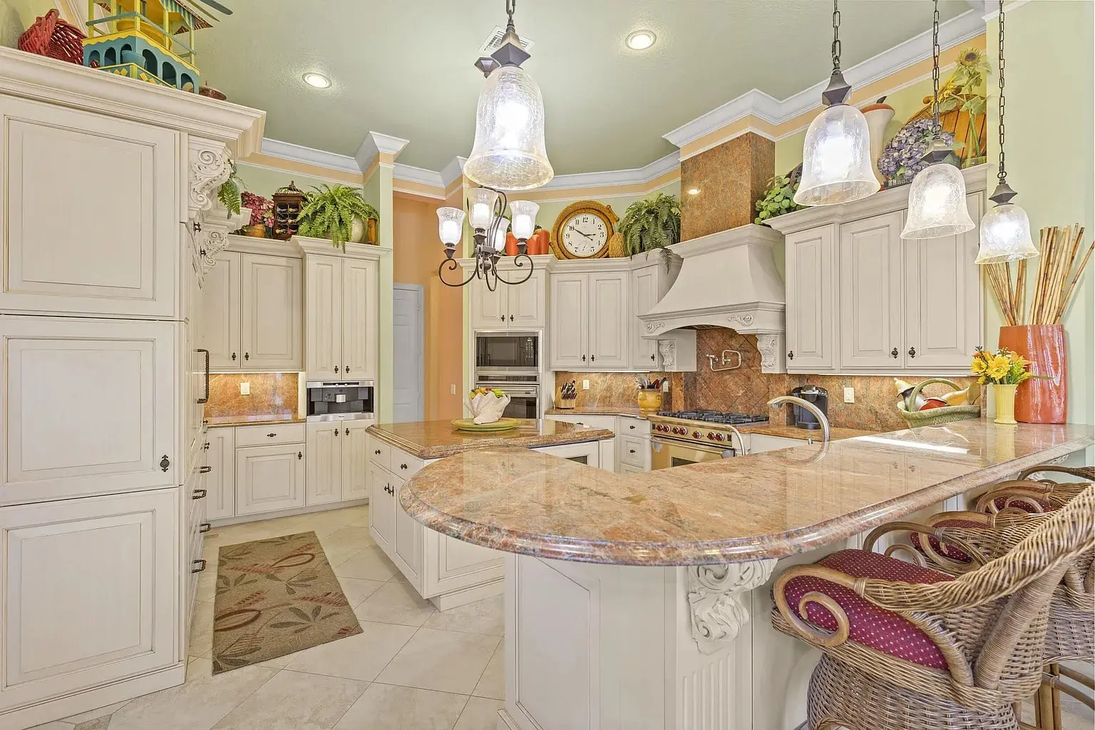Spacious kitchen with white cabinets, granite countertops, hanging lights, and decorative plants.