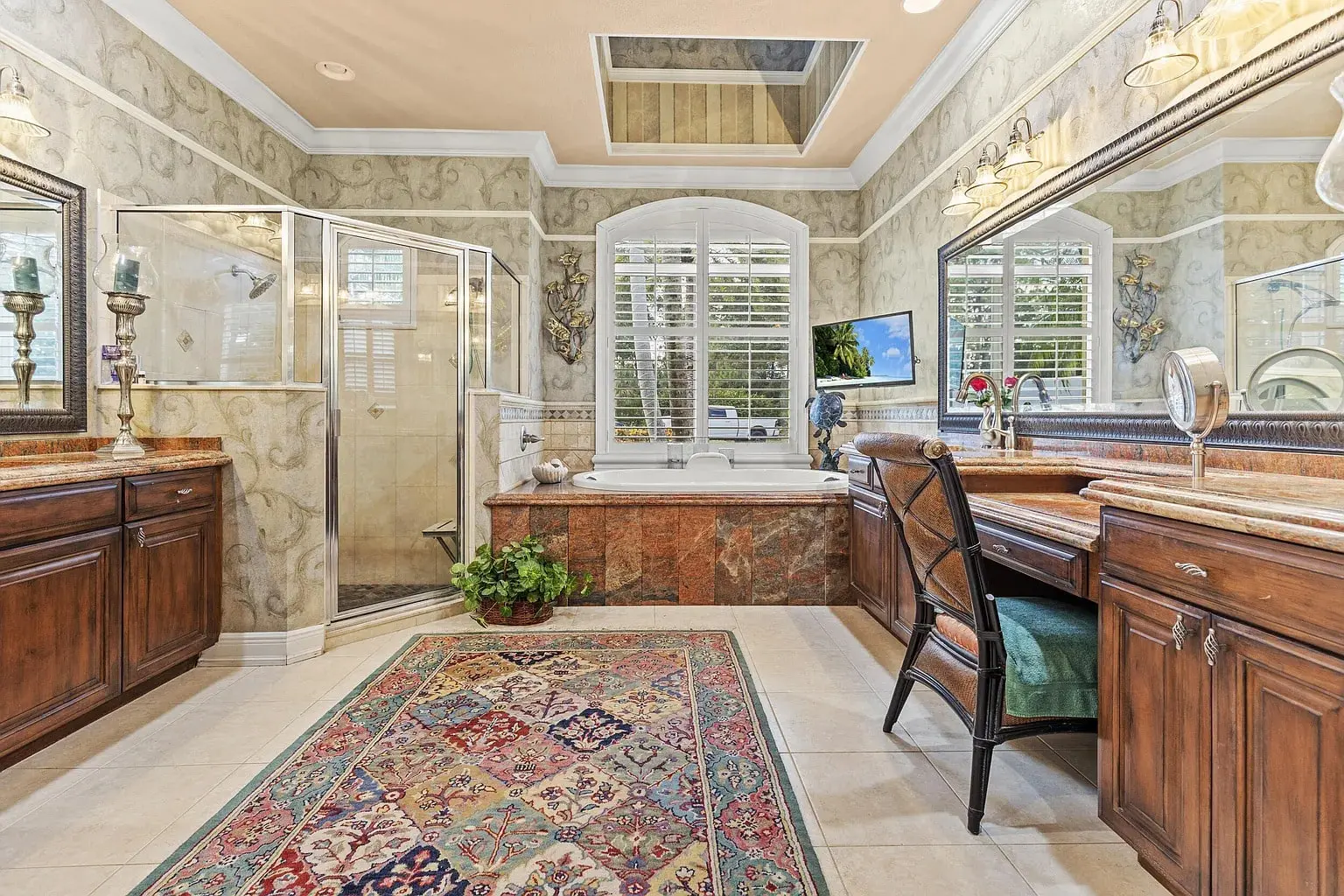 Luxurious bathroom with a large tub, glass shower, double sinks, and ornate decor.