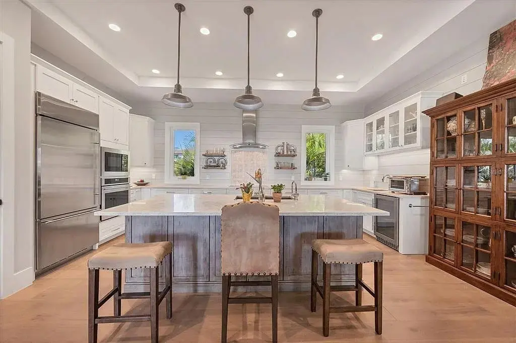 Modern kitchen with a large island, pendant lights, and stainless steel appliances.