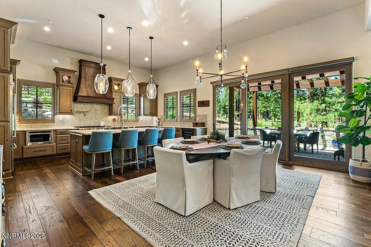 Modern kitchen and dining area with wooden floors, large windows, and outdoor patio view.