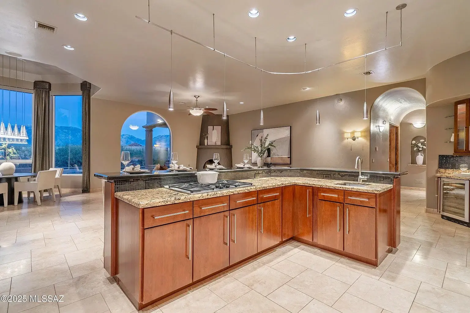 Spacious modern kitchen with granite countertops, wooden cabinets, and dining area with large windows.