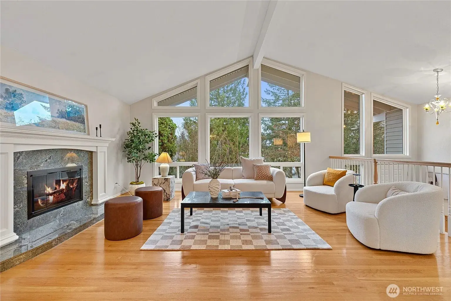 Spacious living room with large windows, modern furniture, fireplace, and wooden floor.