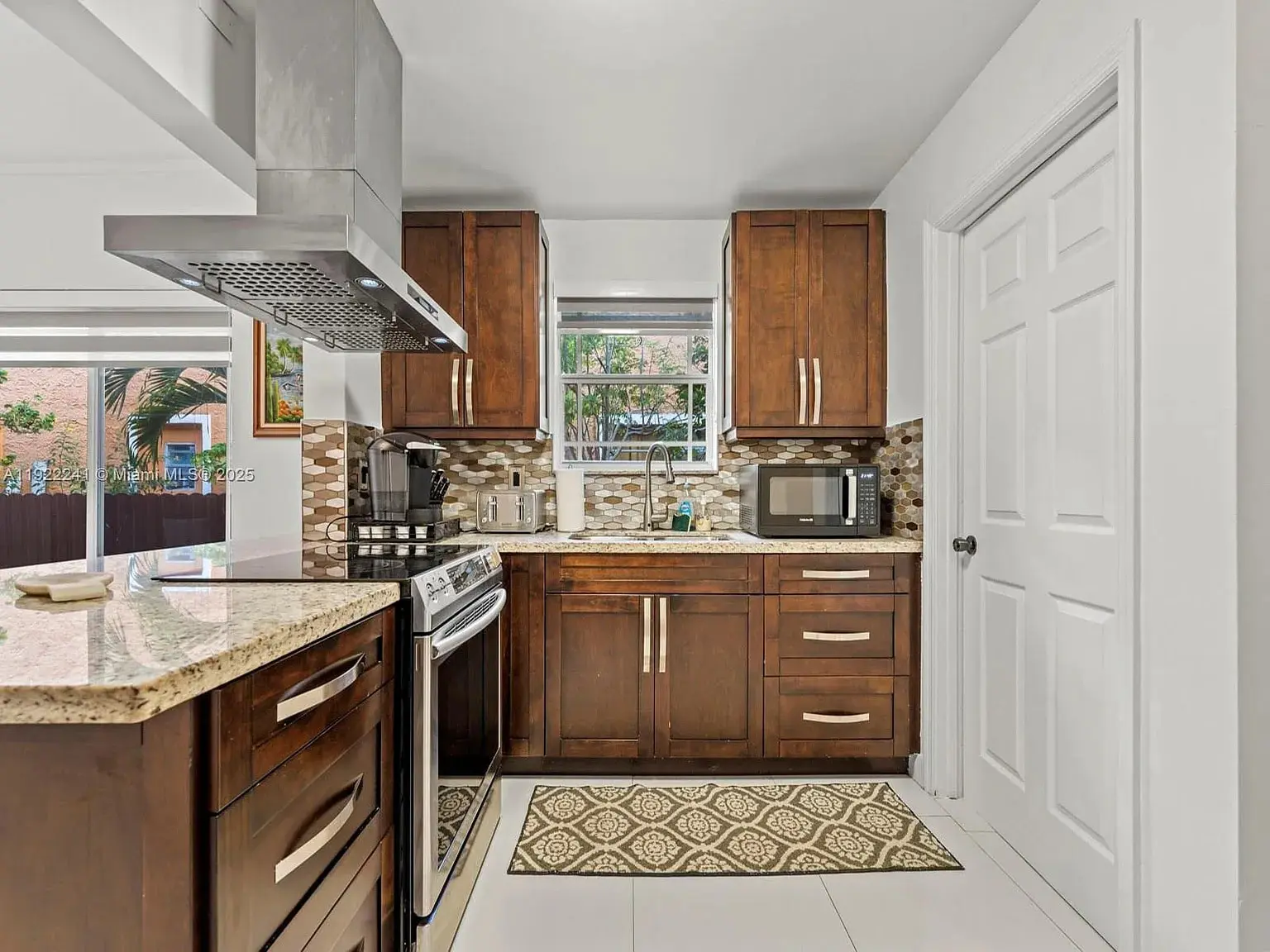 Modern kitchen with wooden cabinets, stainless steel appliances, and a patterned rug on the floor.