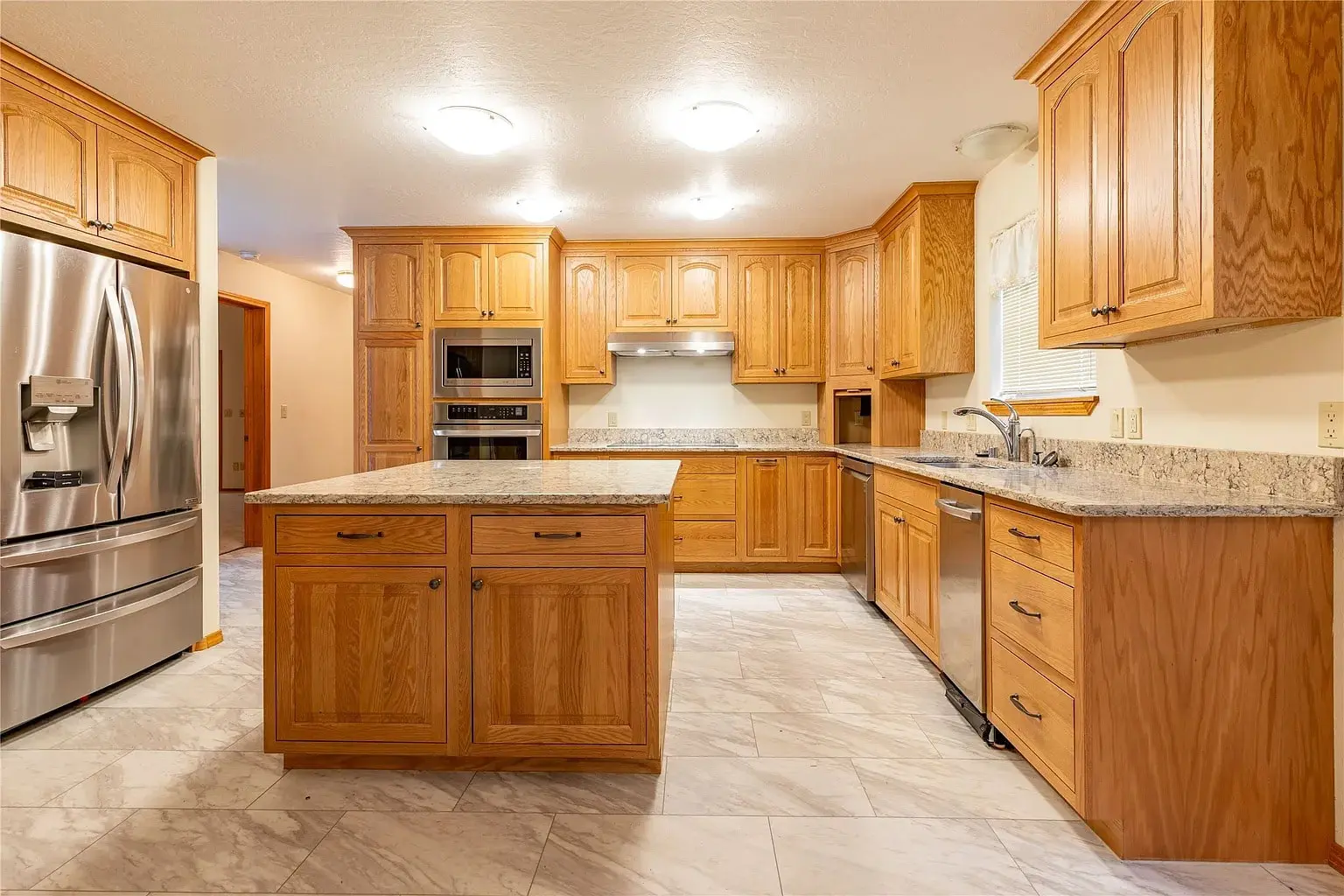 Spacious kitchen with wooden cabinets, granite countertops, stainless steel appliances, and a central island.