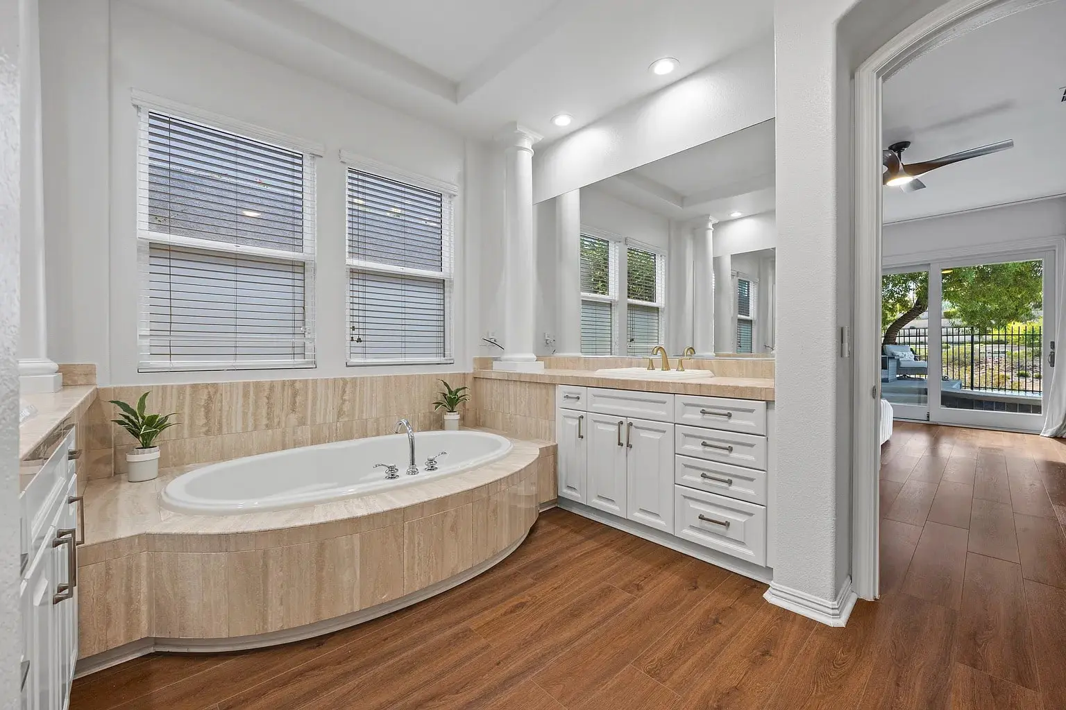 Modern bathroom with a large bathtub, double sink vanity, and wooden flooring.