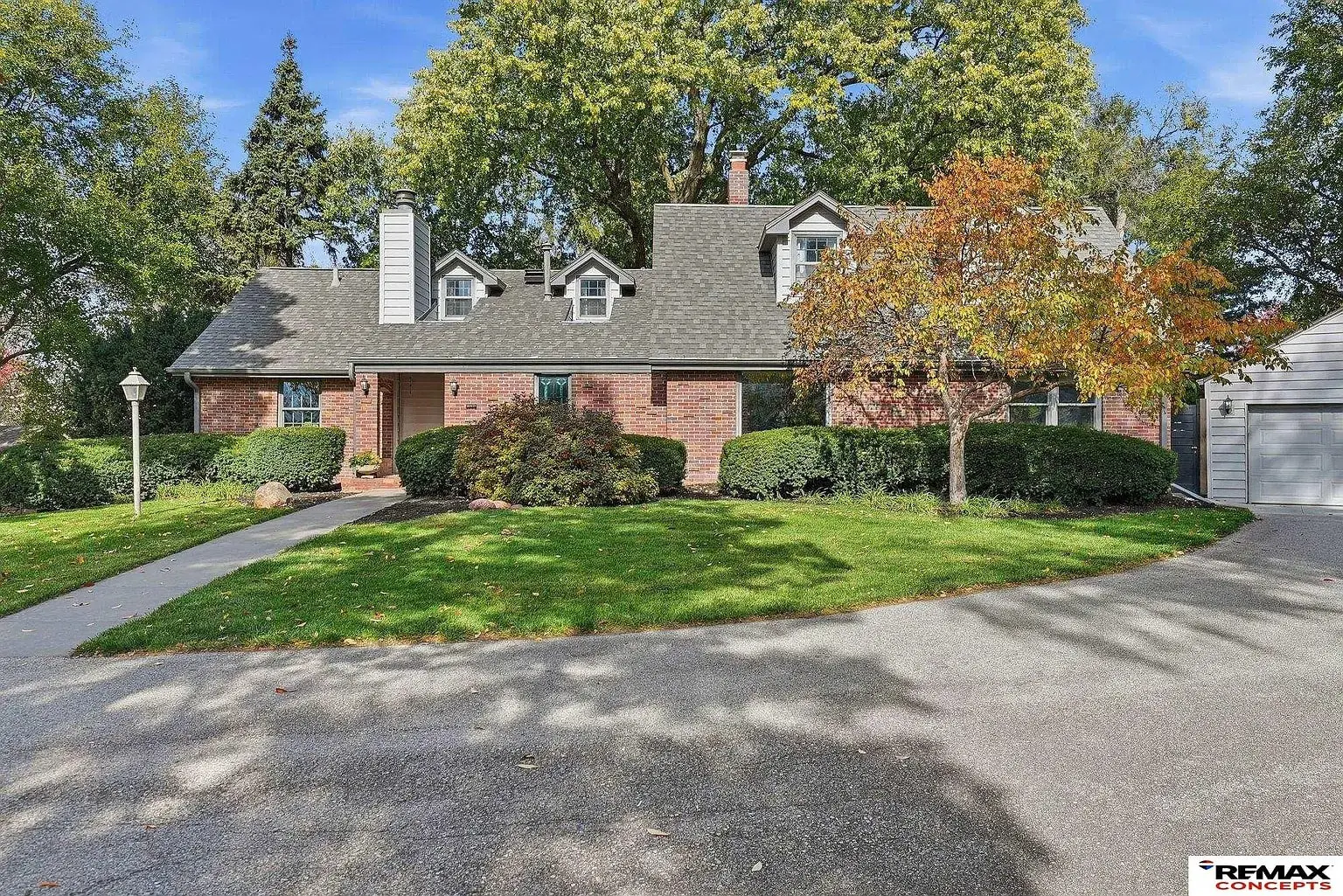 Brick house with a gray roof, surrounded by trees and a curved driveway.