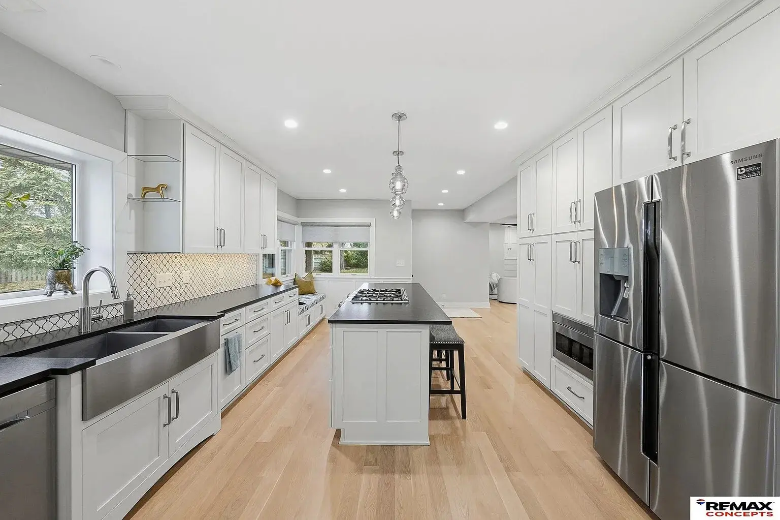 Modern kitchen with white cabinets, stainless steel appliances, island, and large farmhouse sink.