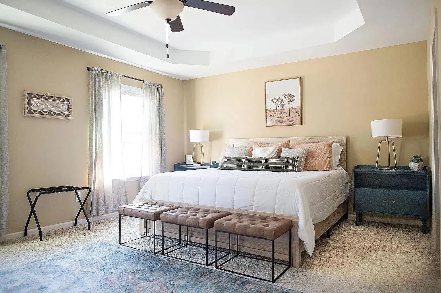 Bedroom with a large bed, two nightstands, lamps, and a ceiling fan. Neutral tones.
