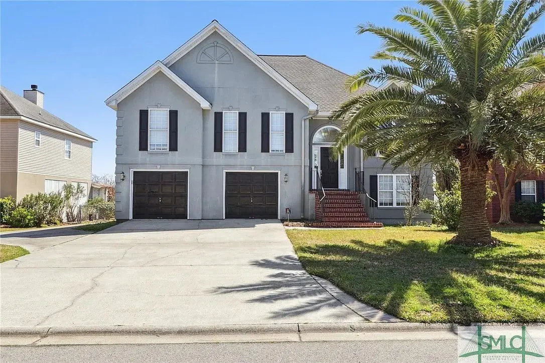 Two-story gray house with double garage, palm tree, and brick steps leading to entrance.