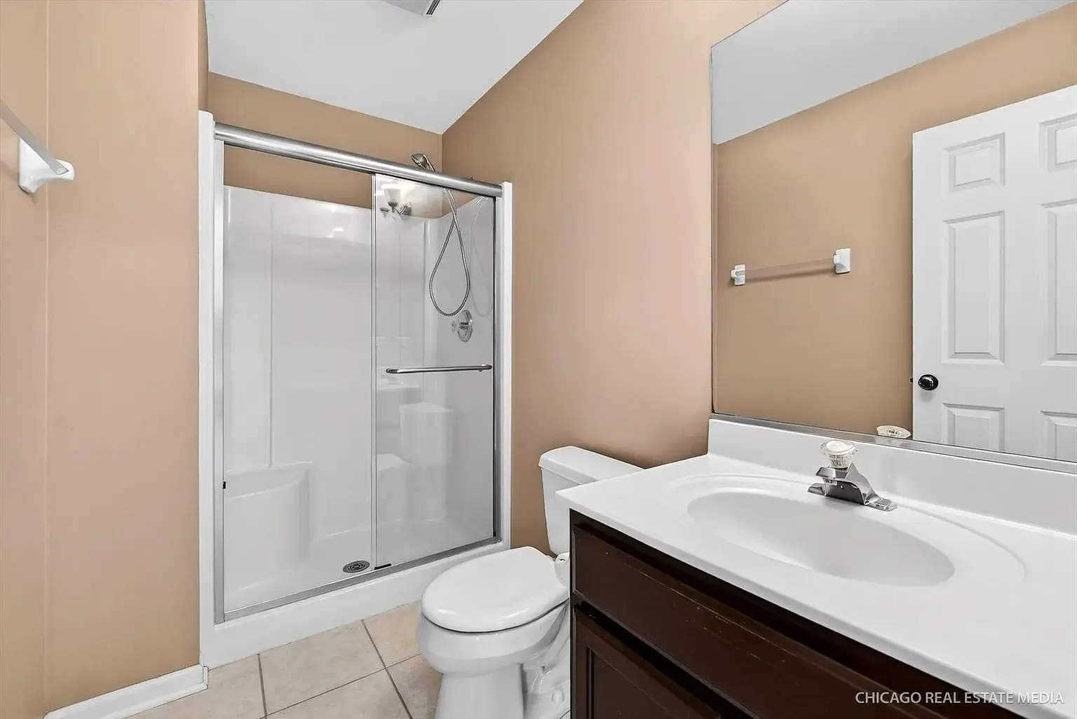 Bathroom with a shower, toilet, and sink with a large mirror above.