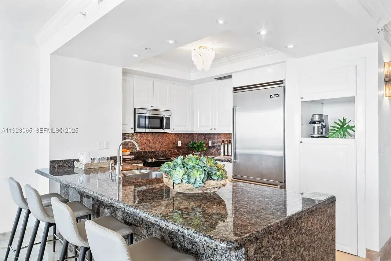 Modern kitchen with granite countertops, stainless steel appliances, and bar seating for four.
