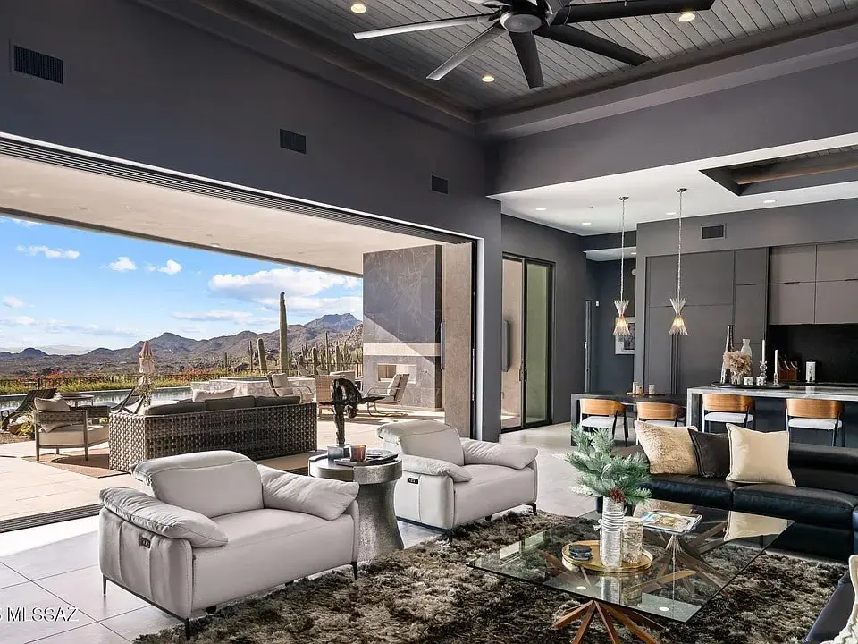 Modern living room with large open sliding doors to a desert landscape, featuring stylish furniture.