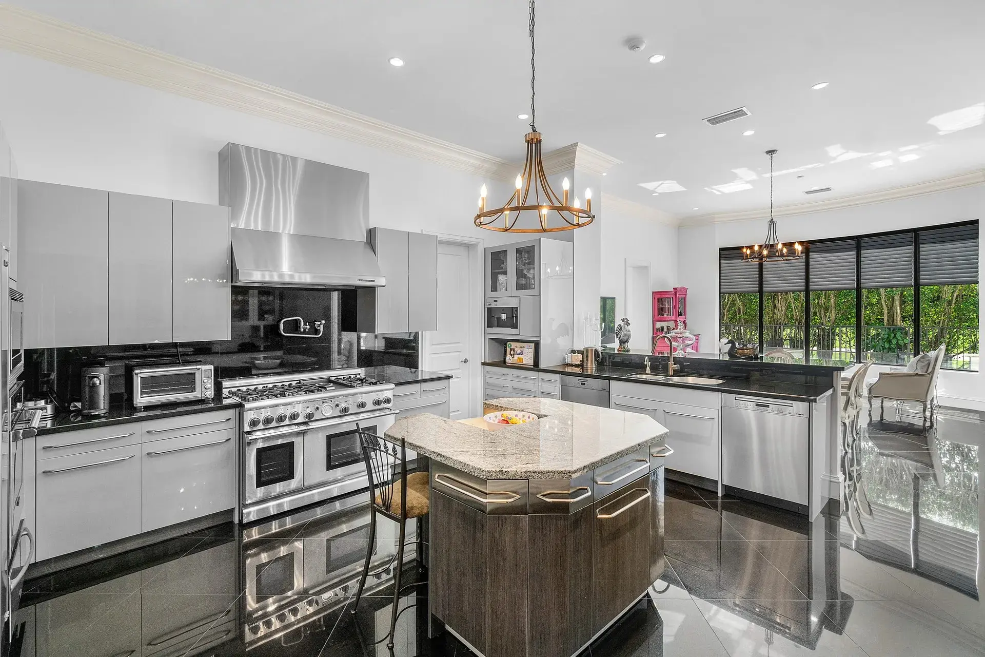 Modern kitchen with stainless steel appliances, island with seating, and large windows providing natural light.