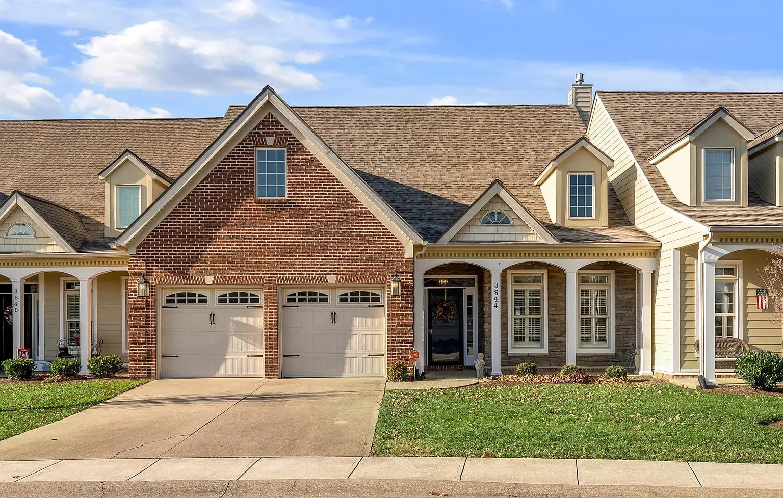 Brick and siding townhouse with a double garage and a small front lawn.
