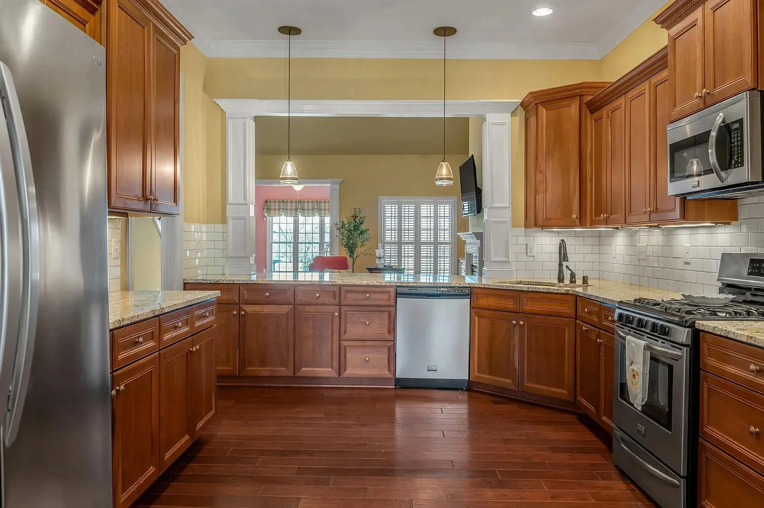 Spacious kitchen with wooden cabinets, stainless steel appliances, and a view into a dining area.