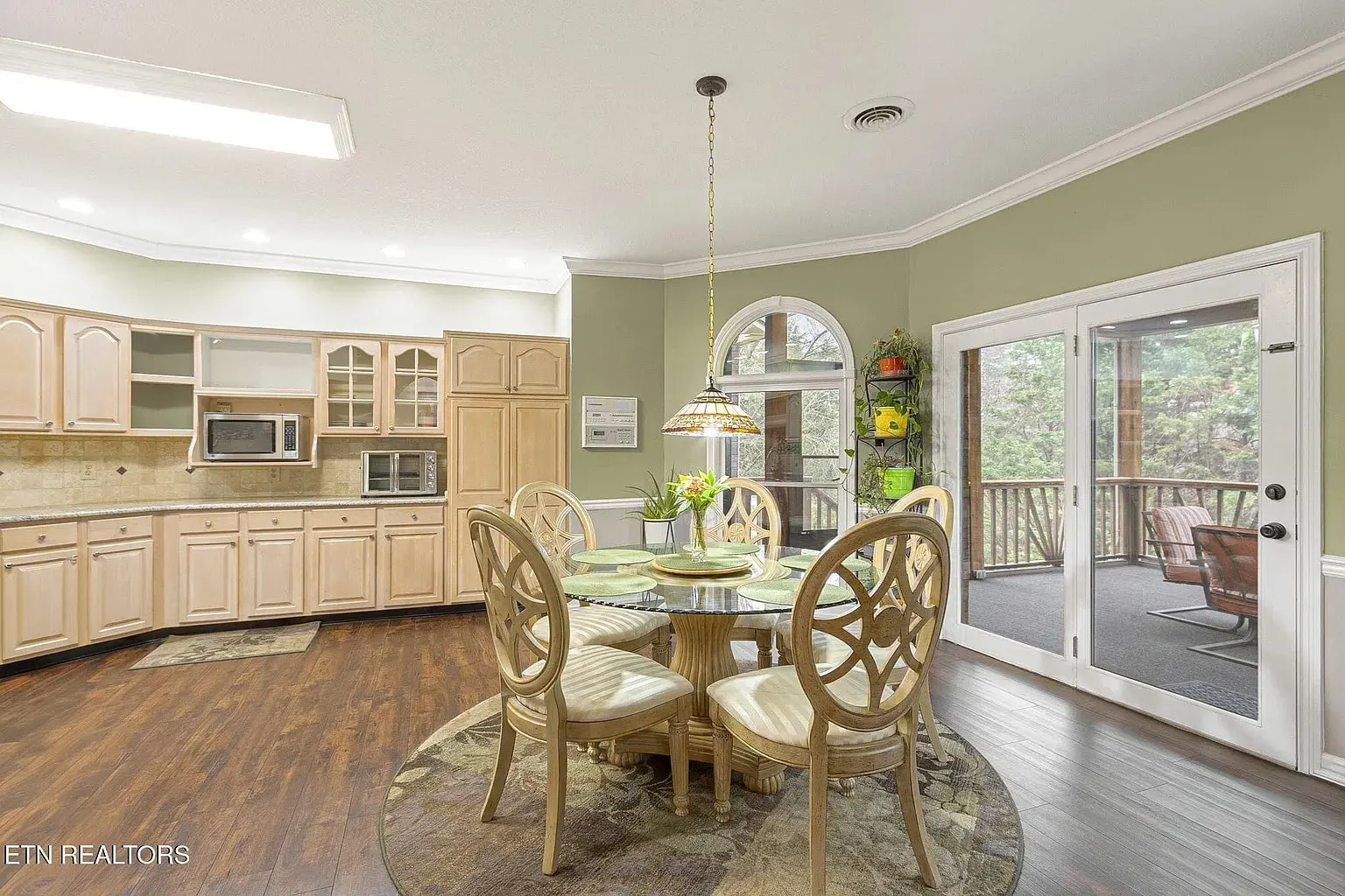 Spacious kitchen with wooden cabinets, round dining table, and access to a screened porch.