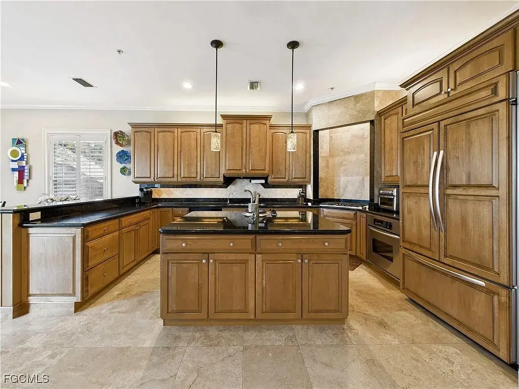 Spacious kitchen with wooden cabinets, black countertops, and stainless steel appliances.