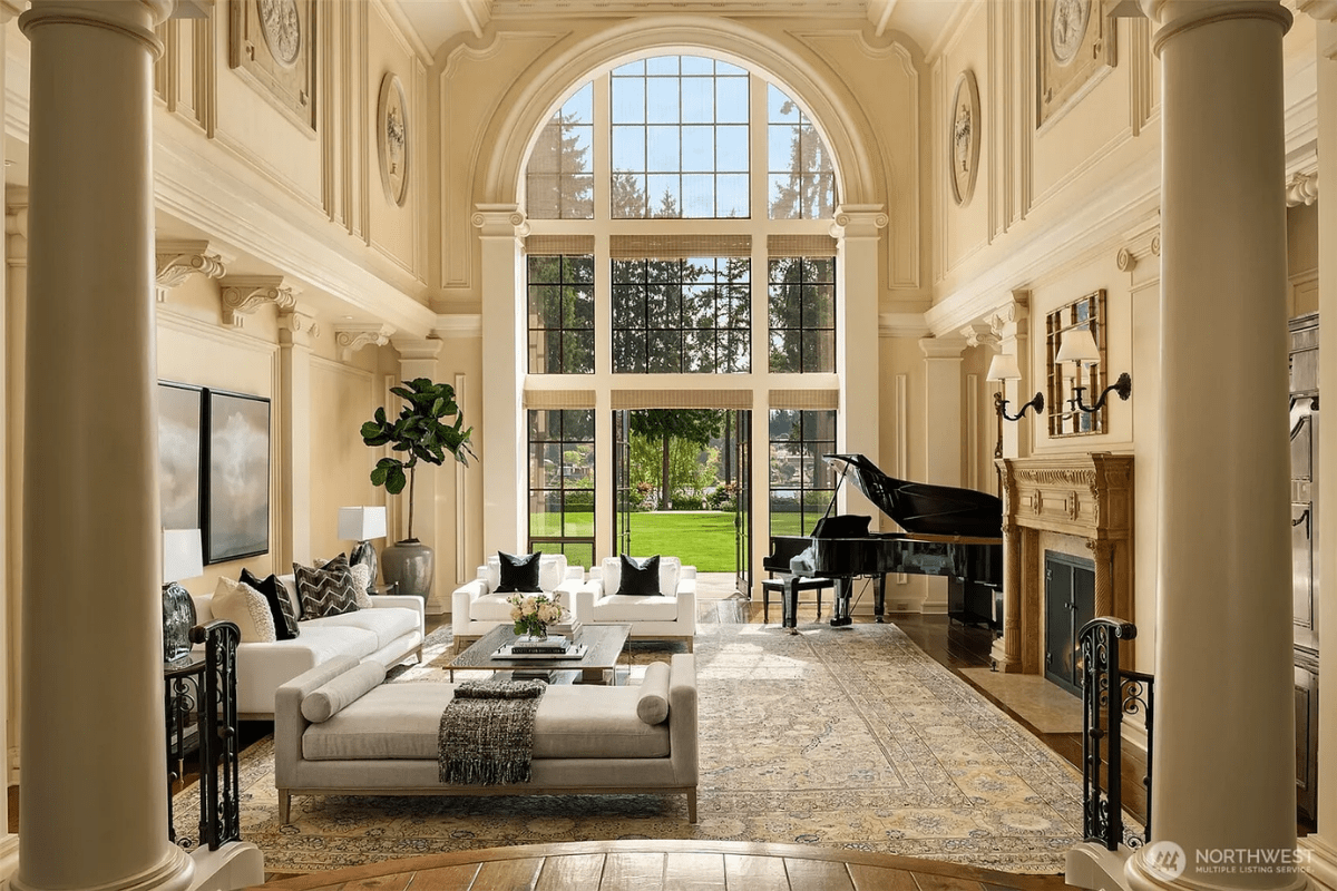 A grand living room with a piano, a couch, art, a fireplace, and a view directly outside.