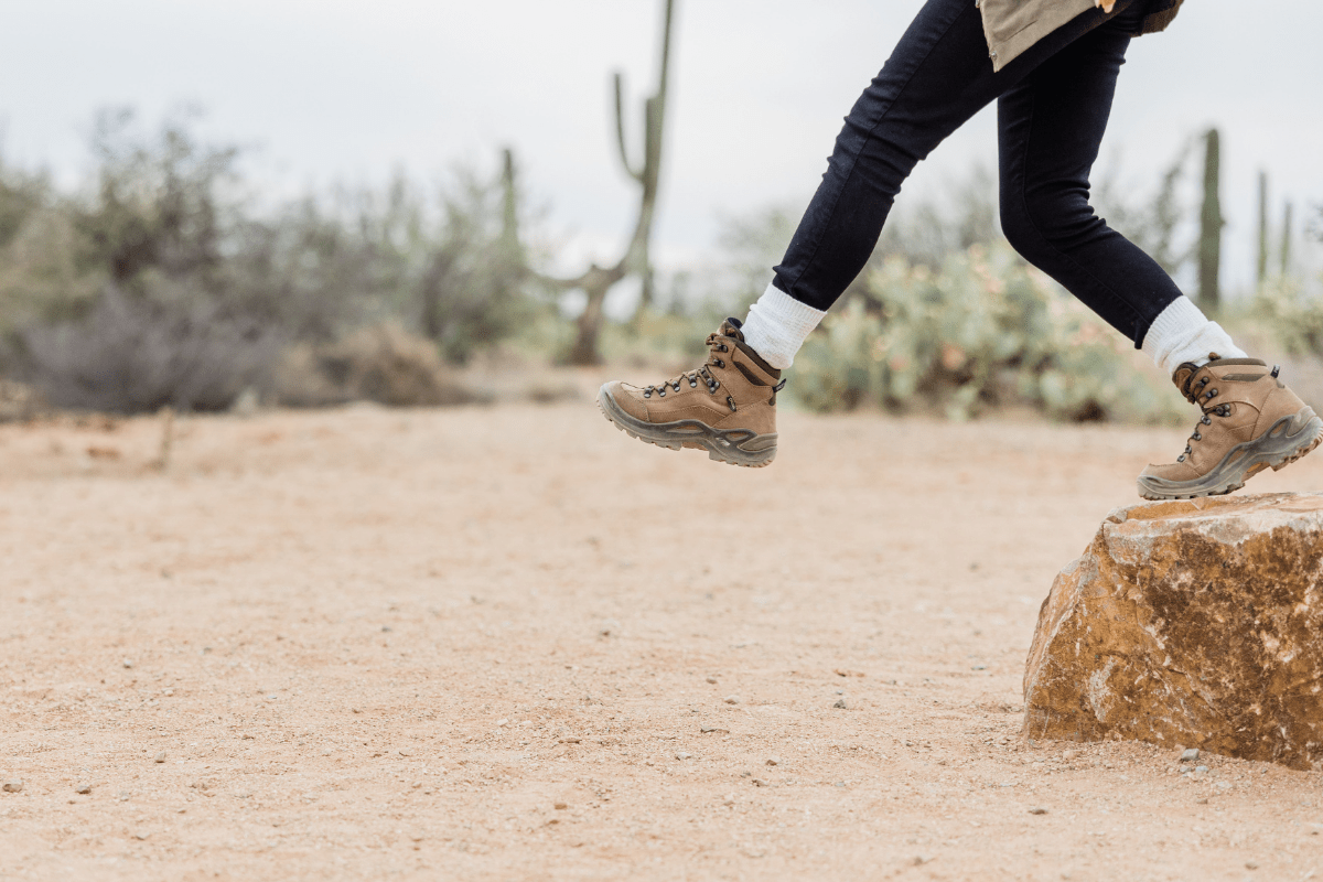 A hiker stepping down from a rock in the desert.