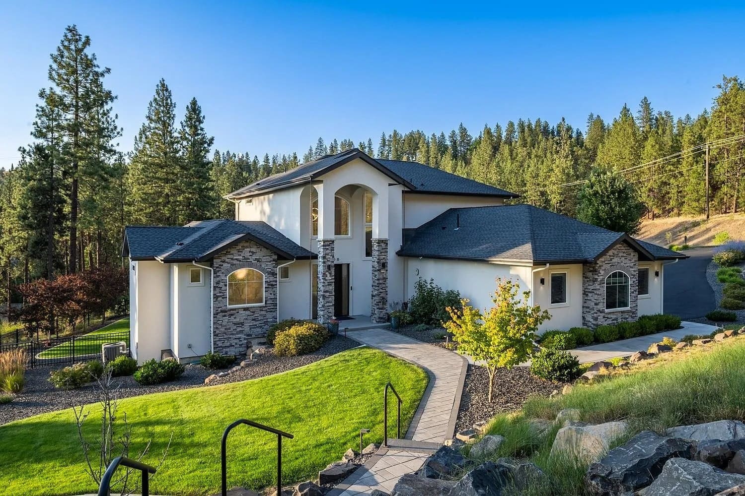 Modern two-story house with stone accents, surrounded by trees and a well-maintained lawn.