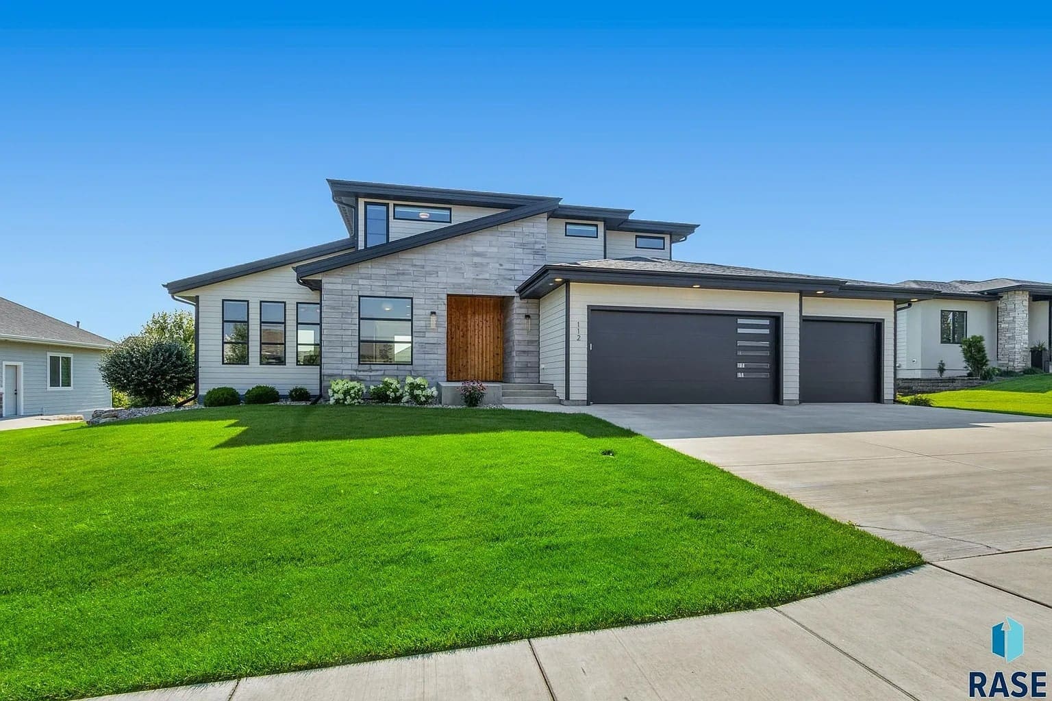 Modern two-story house with large windows, gray exterior, and a three-car garage.