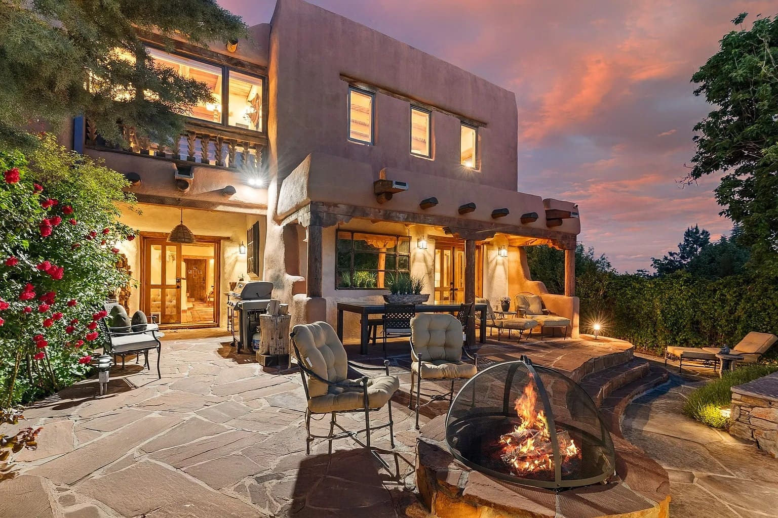 Southwestern-style house with patio, fire pit, and outdoor seating at sunset.