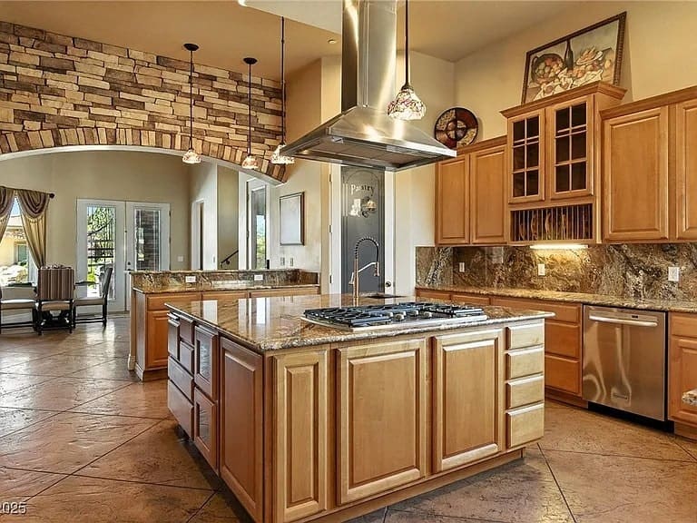 Spacious kitchen with wooden cabinets, large island, stone accents, and stainless steel appliances.