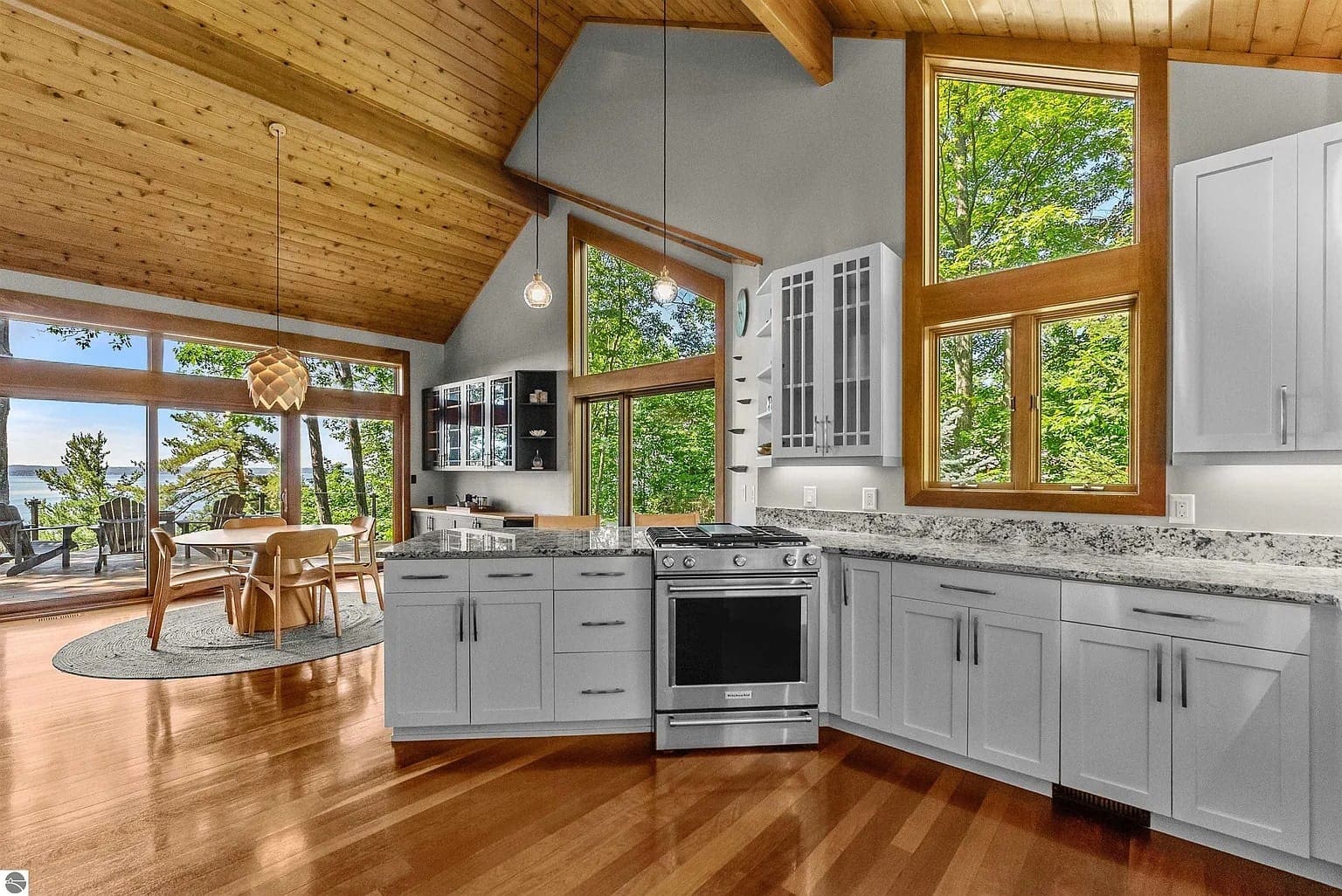 Spacious kitchen and dining area with large windows, wooden ceiling, and outdoor view.