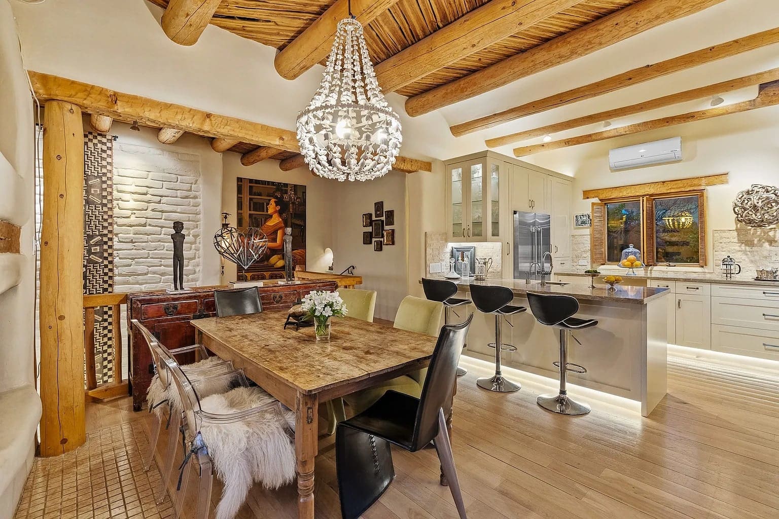 Rustic kitchen and dining area with wooden beams, chandelier, and modern appliances. Cozy and elegant decor.