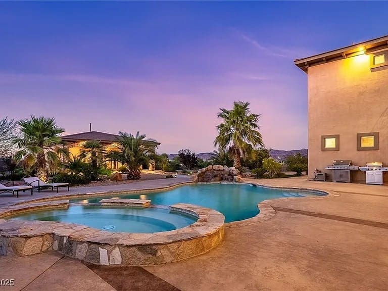 Backyard with a swimming pool, palm trees, and a patio at sunset.