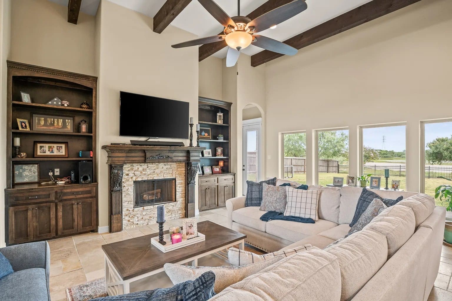 Spacious living room with a large sectional sofa, fireplace, and wall-mounted TV, overlooking a backyard.