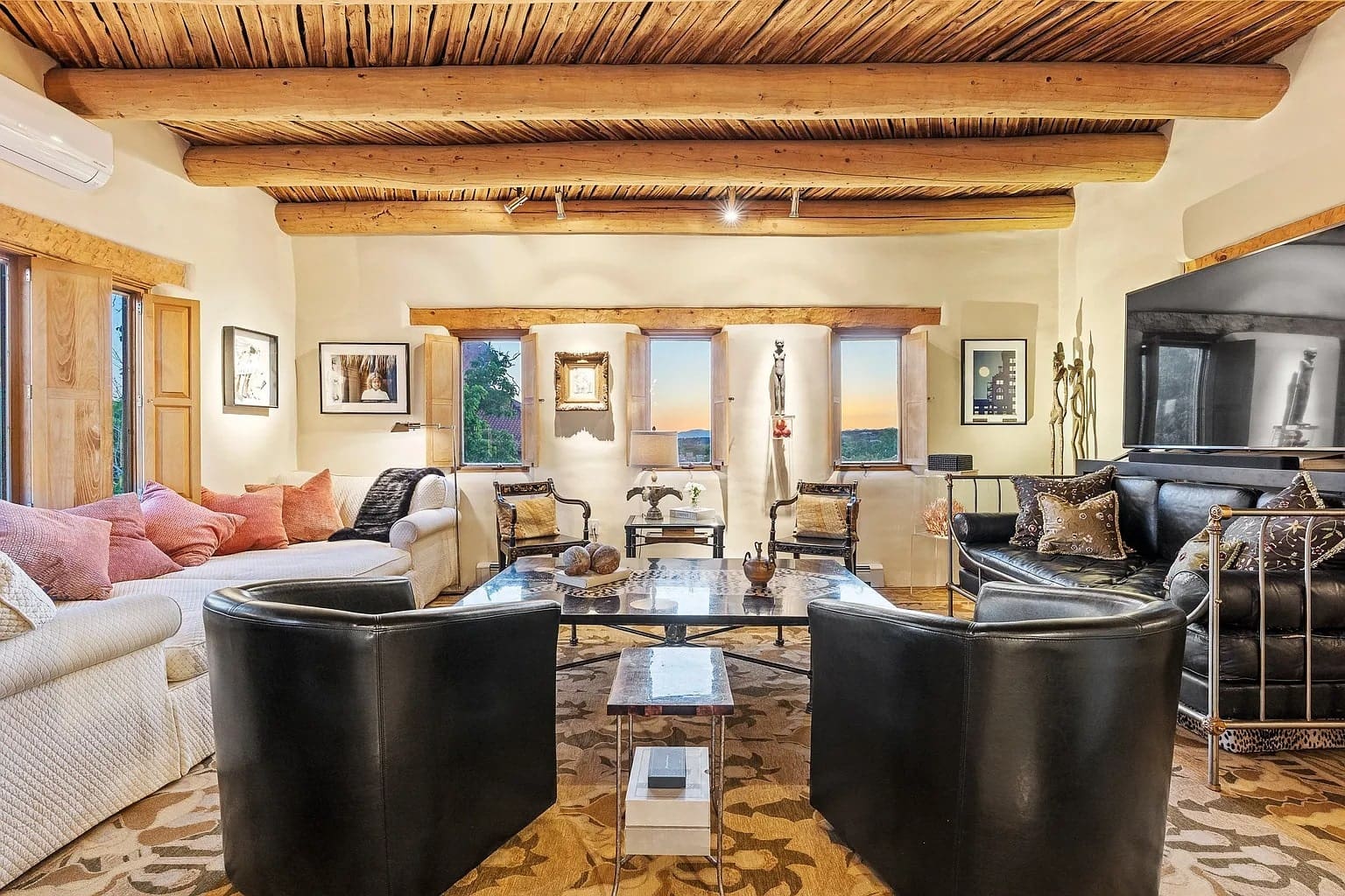 Cozy living room with wooden beams, modern furniture, and large windows showcasing a scenic view.