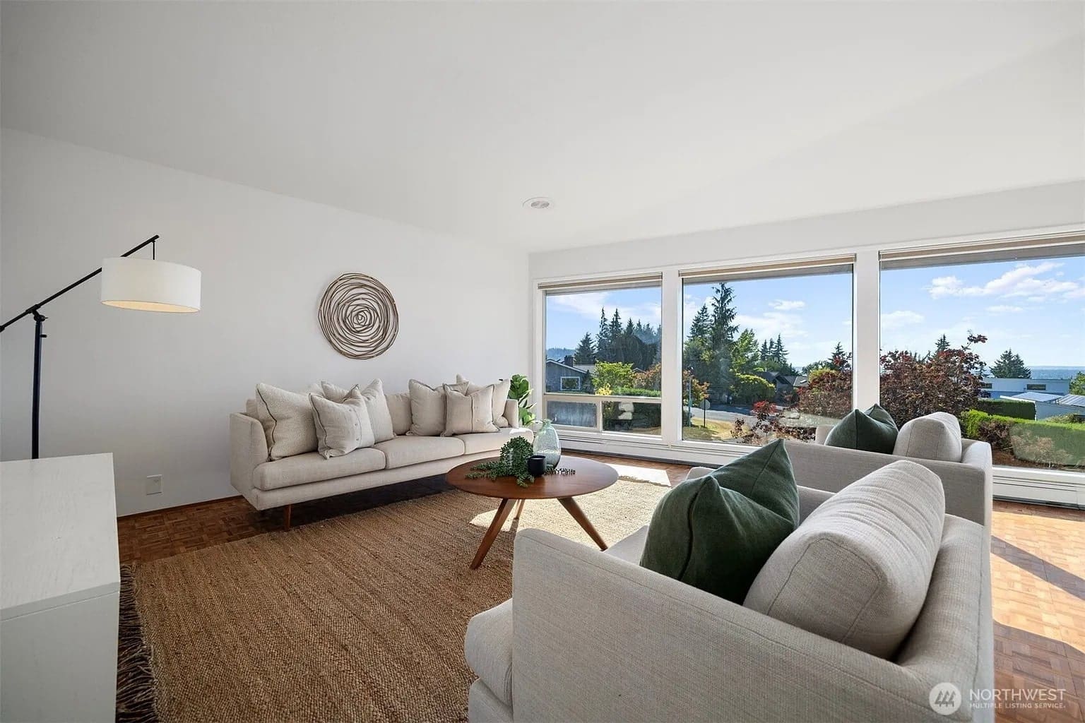 Bright living room with modern furniture, large windows, and a scenic outdoor view.