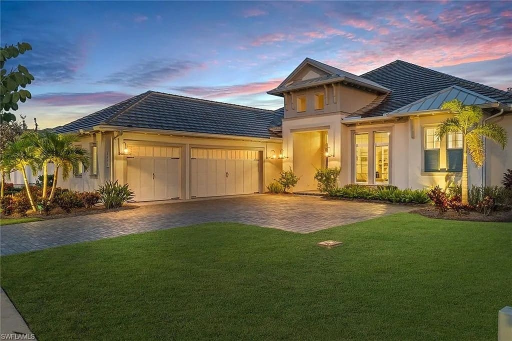 Single-story house with a three-car garage, surrounded by a manicured lawn at sunset.
