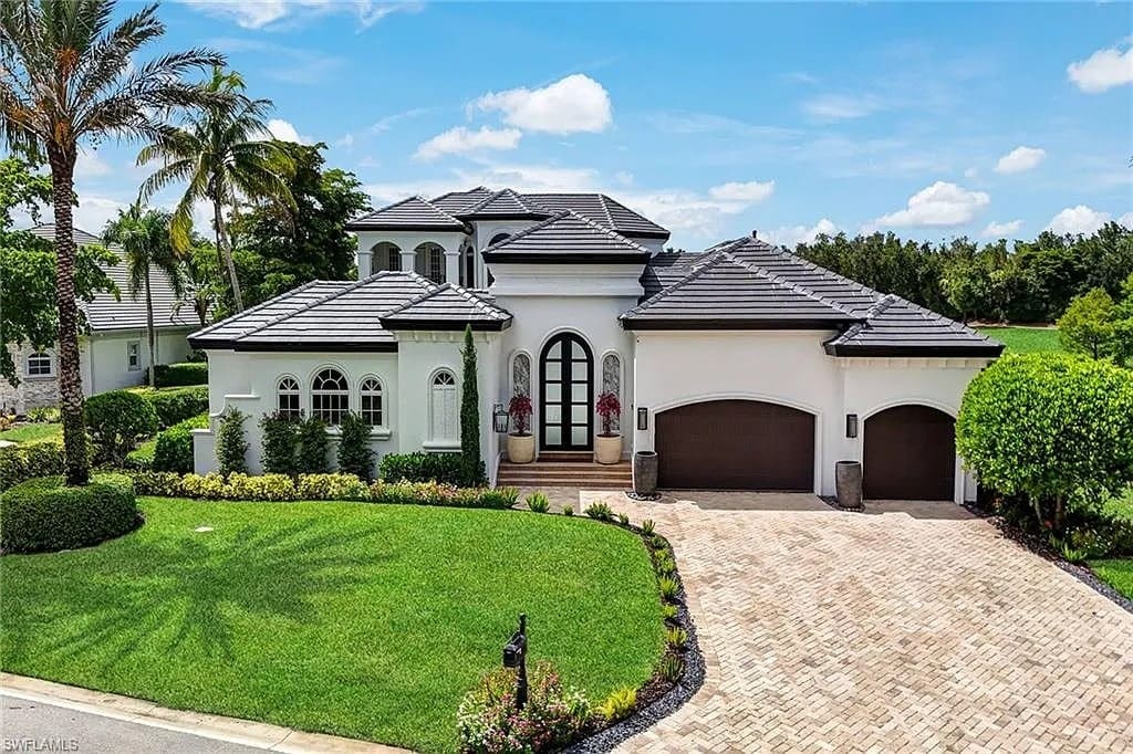 Elegant two-story white house with arched windows, palm trees, and a three-car garage.